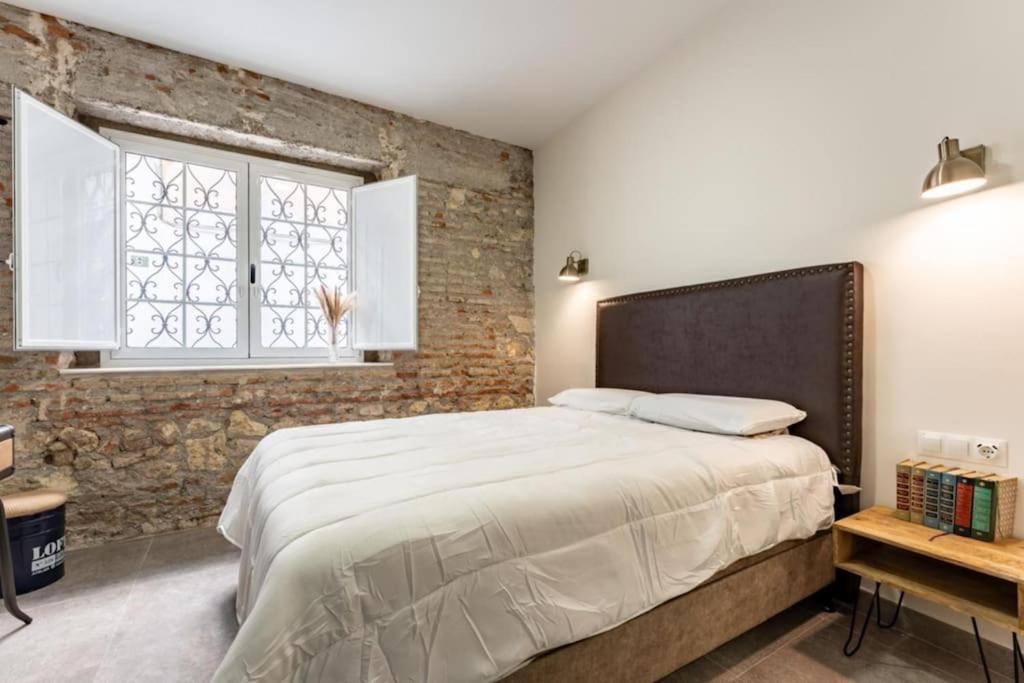 - une chambre avec un grand lit et un mur en briques dans l'établissement Estrena Apartamento en centro historico de Almeria, à Almería