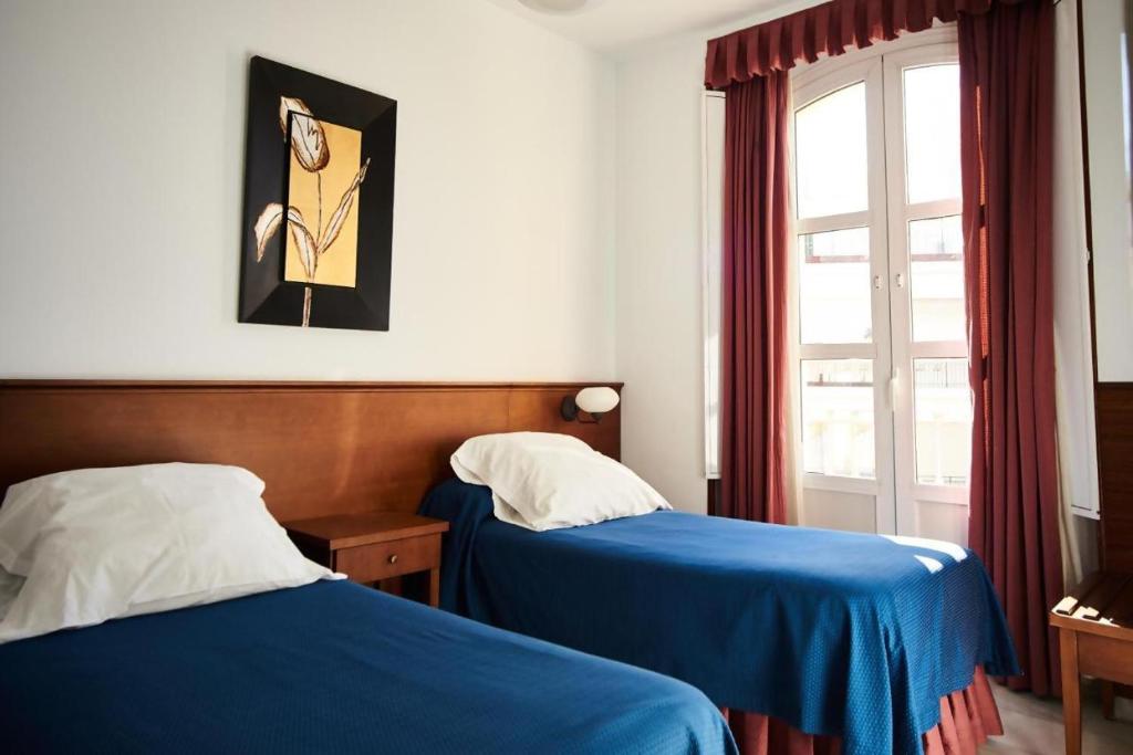 セビリアにあるアパルタメントス サン アンドレスのベッド2台と窓が備わるホテルルームです。