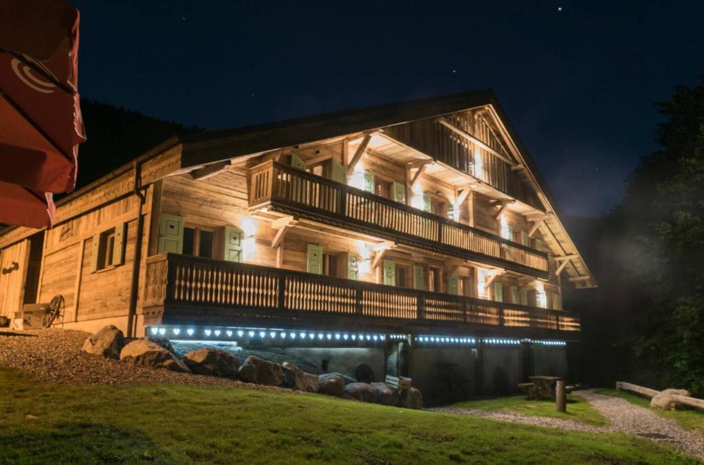 um grande edifício de madeira com luzes à noite em Ferme Champ'alp em Abondance