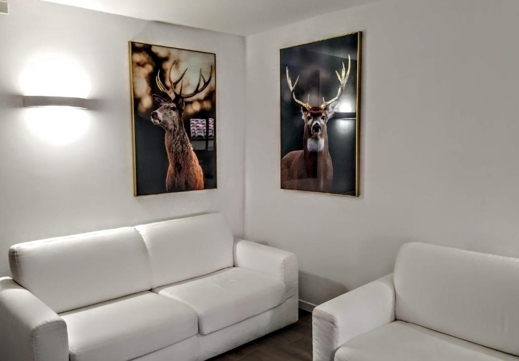 a living room with two paintings of deer on the wall at Casa Micisca - Pescasseroli Centro in Pescasseroli