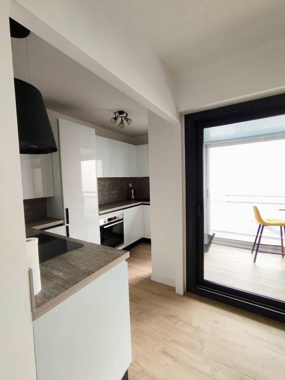 une cuisine avec des placards blancs et une grande fenêtre dans l'établissement Le Panorama de la Corniche, à Saint-Hilaire-de-Riez