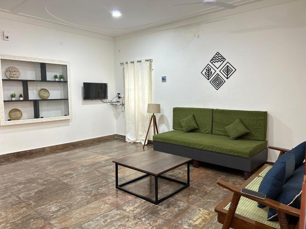 HOMESTAY - AC 3 BHK NEAR AlRPORT في تشيناي: غرفة معيشة مع أريكة خضراء وطاولة