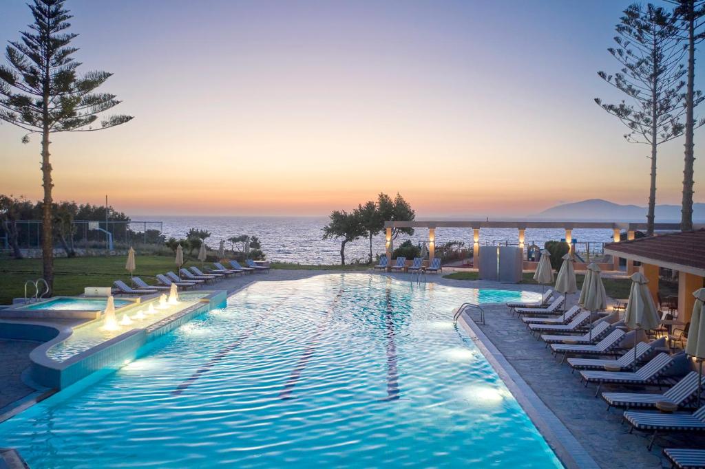 a swimming pool with lounge chairs and the ocean at Ammos Luxury Resort in Mastichari