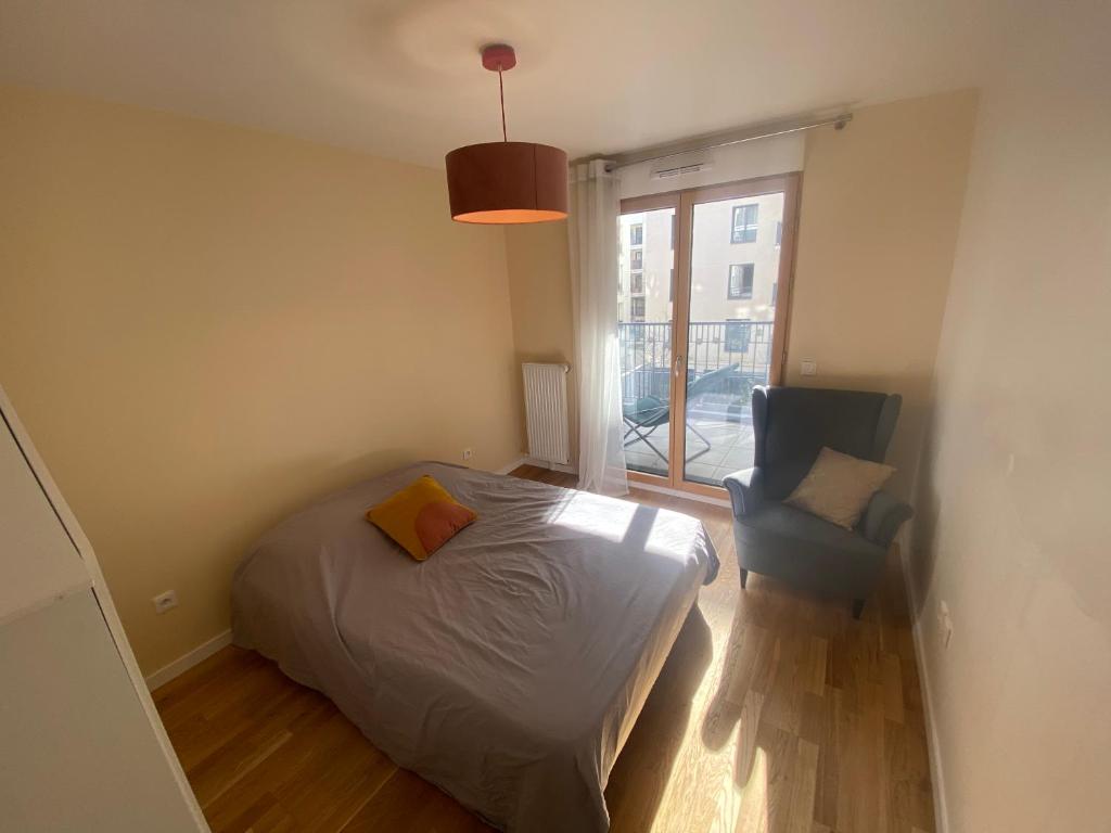 um quarto com uma cama, uma cadeira e uma janela em Sérénité totale : appartement ensoleillé em Clichy
