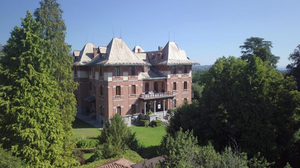 un viejo castillo con árboles delante de él en Villa Cernigliaro Dimora Storica, en Sordevolo