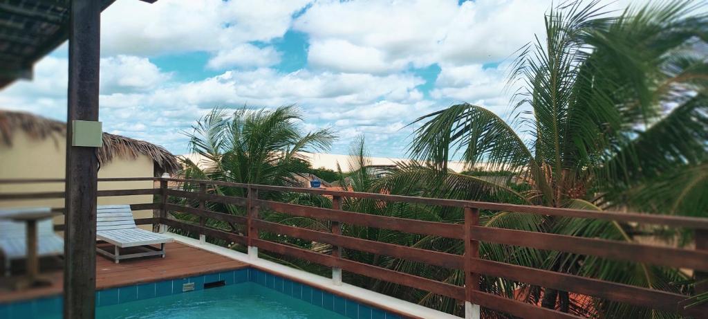 a balcony with a bench and a swimming pool at Pousada Tropical Brasil Jeri in Jericoacoara