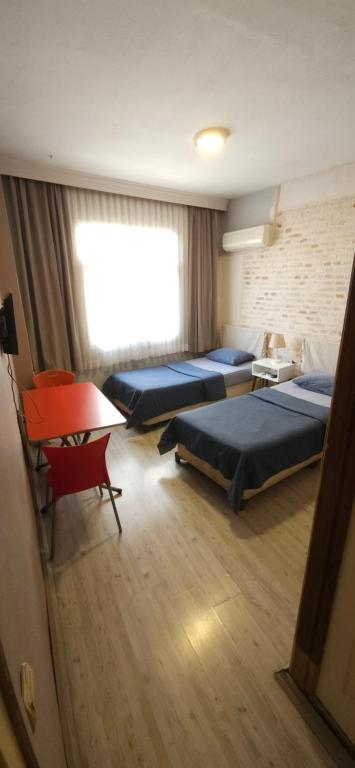 アダナにあるÜnver Hotelのベッド3台と赤い椅子が備わる部屋