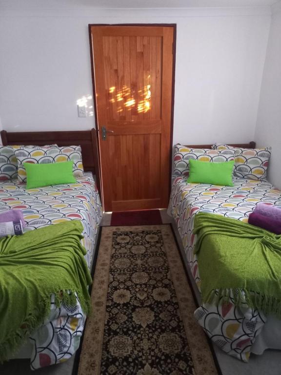 two beds in a room with green pillows and a door at Eloff's Guest House in Polokwane