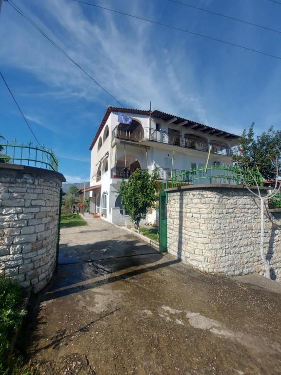 a white building with a gate and a stone wall at Guest house Irvin in Berat