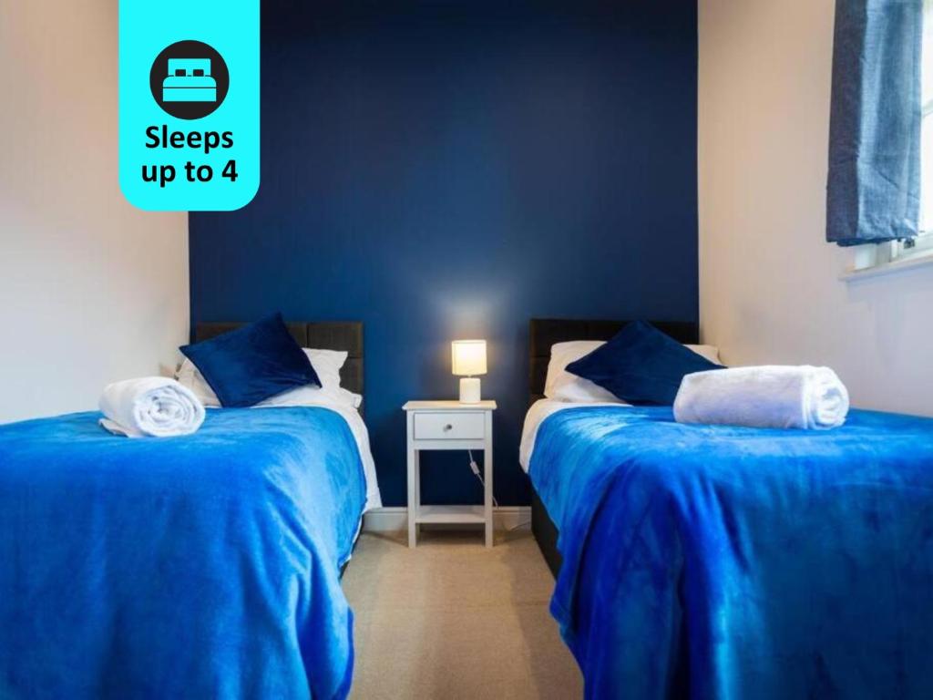 two beds in a room with blue walls at Charlotte House - The Stylish Sanctuary in Central Ipswich in Ipswich