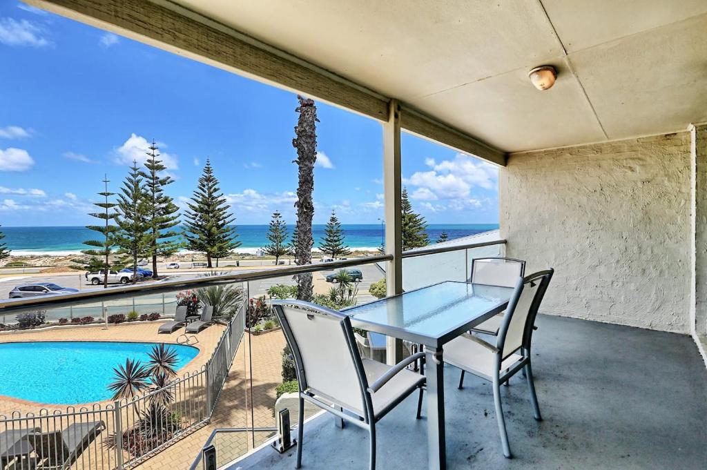 a balcony with a table and chairs and a swimming pool at Scarborough Beach Front Resort - Shell Seven in Perth