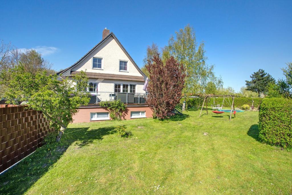 a house with a yard with a swing at Rügenferienhaus eg und og in Schaprode