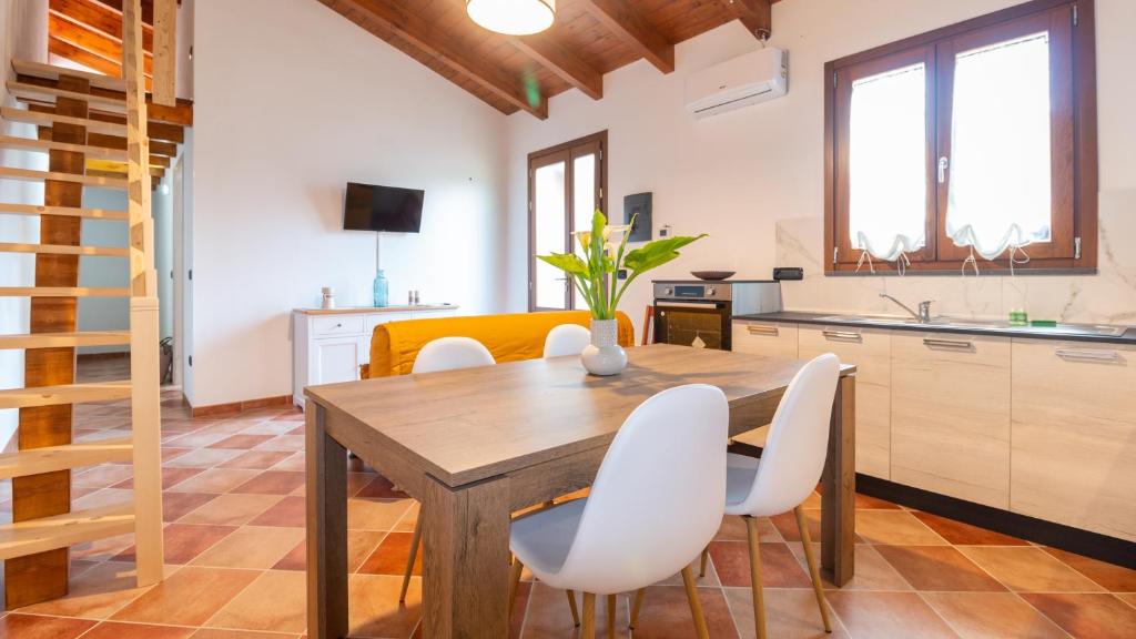una cucina e una sala da pranzo con tavolo in legno e sedie bianche di Welcomely - Domo Mea Apartment a Càbras