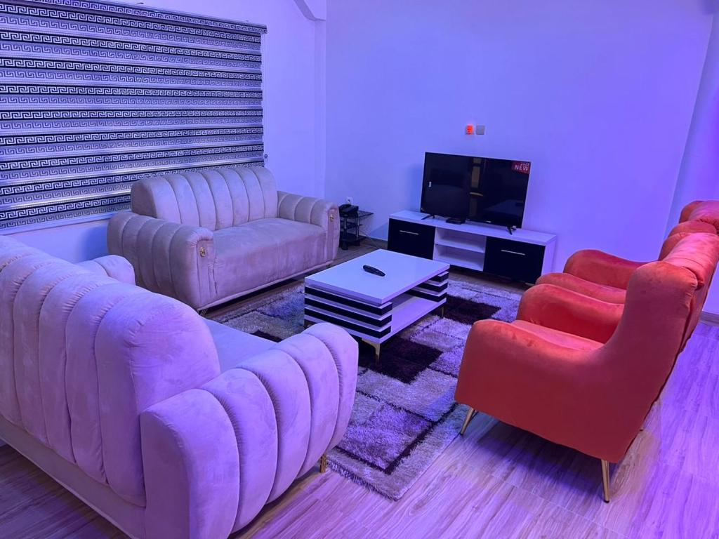 a living room with three couches and a tv at La bonté in Abomey-Calavi