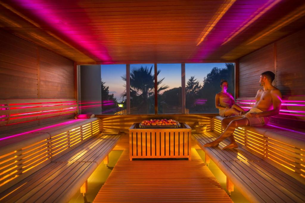 two men sitting on a bench in a room with lights at Aminess Vival Maestral Hotel in Novigrad Istria