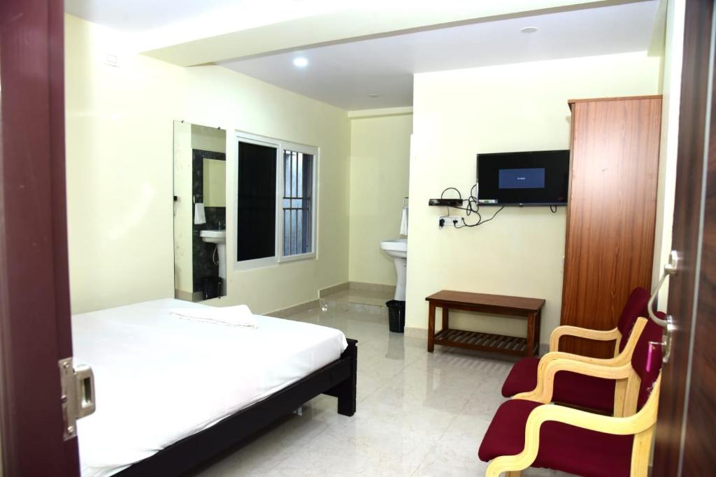 a bedroom with a bed and a chair and a tv at ARUNA GRAND in Visakhapatnam
