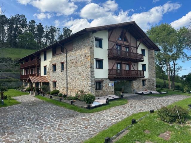 - un grand bâtiment avec un balcon sur le côté dans l'établissement Hotel-Apartamento Rural Atxurra, à Bermeo