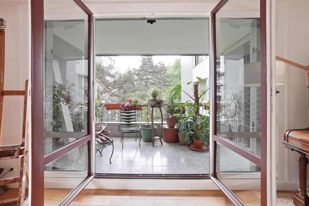 une porte coulissante en verre menant à une terrasse ornée de plantes. dans l'établissement Peace and Quiet appartement at Goutte d'Or by Weekome, à Paris