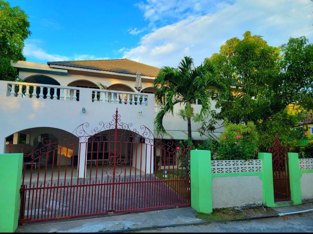 a house with a red gate and a fence at Green's Palace Jamaica in Oracabessa