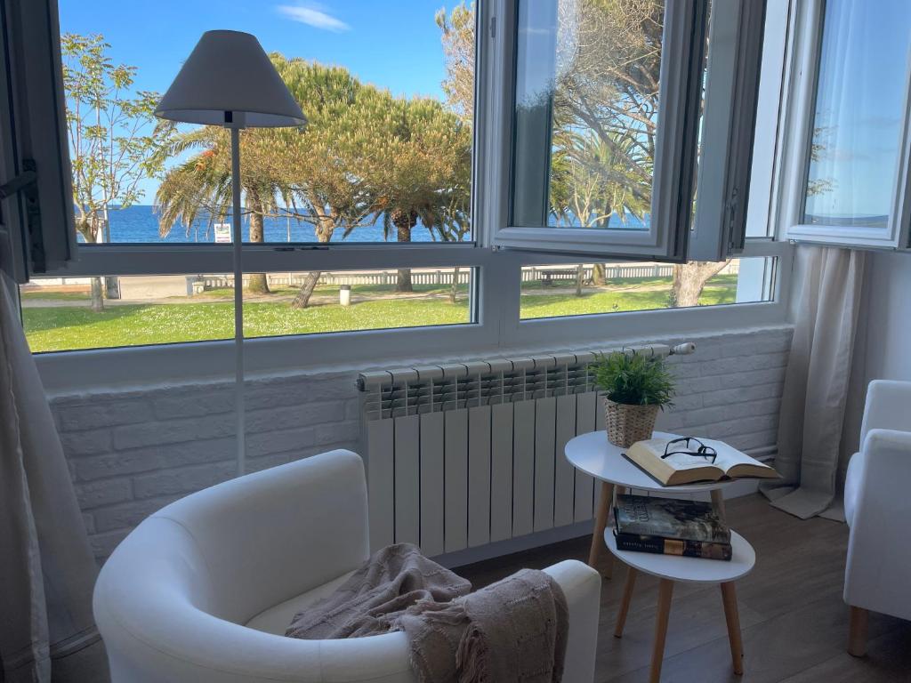 a living room with windows and a chair and a table at Apartamento Comillas Beach in Comillas