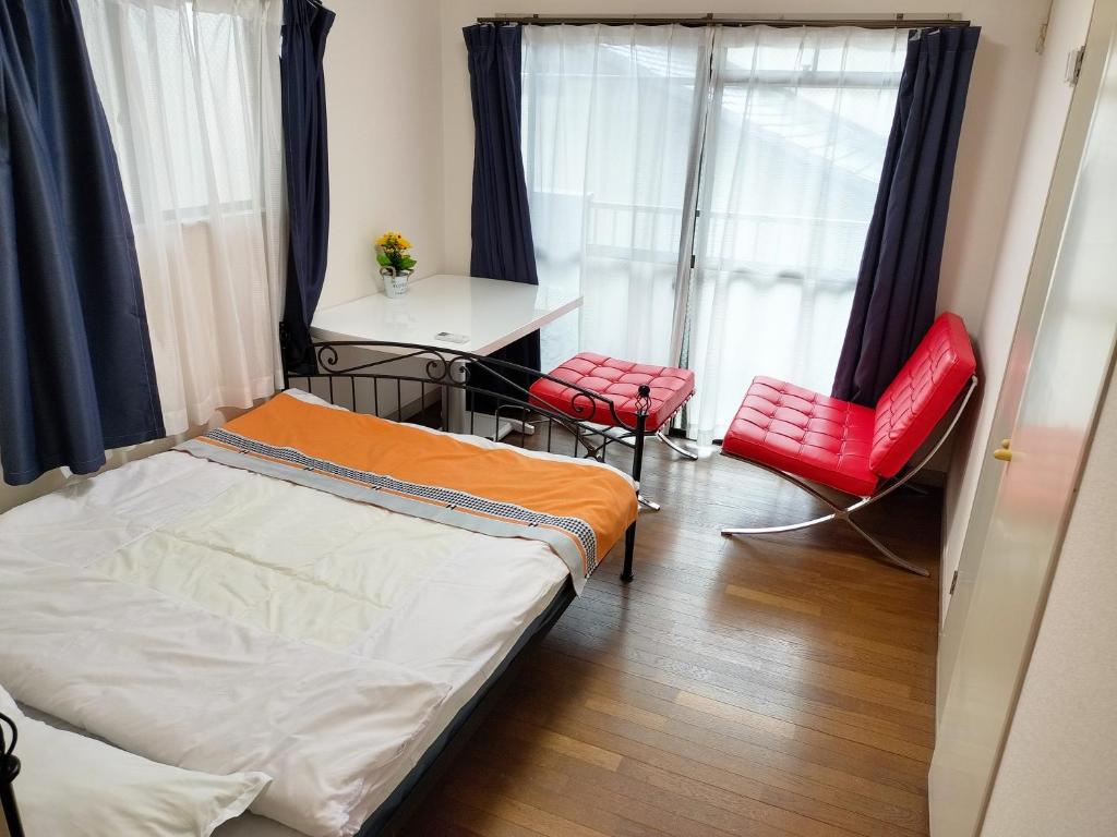 a bedroom with a bed and two red chairs at avanti house姪浜 in Meinohama