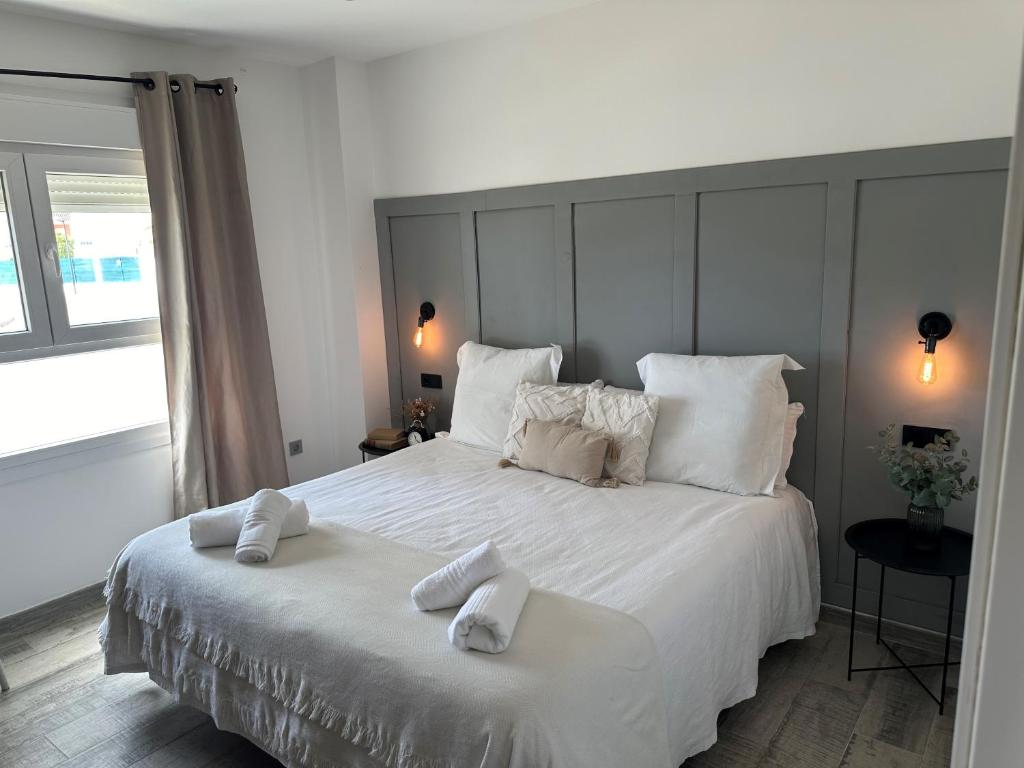a bedroom with a white bed with two towels on it at Pinos del Mar in Huelva