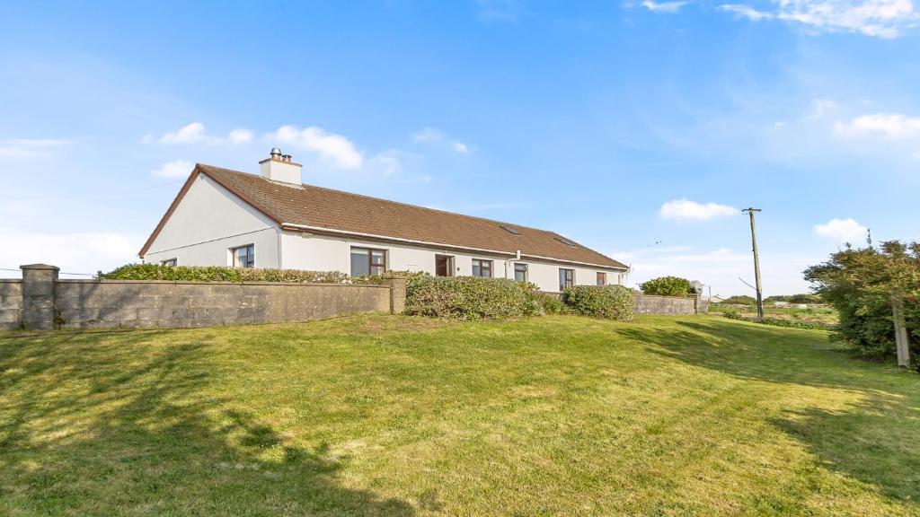 a white house with a fence and a yard at Little Tara, Ballyconneely in Ballyconneely