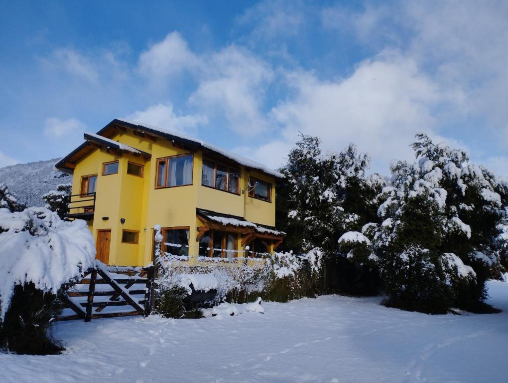 una casa amarilla en la nieve con árboles en Alewekehue , la linda en San Carlos de Bariloche