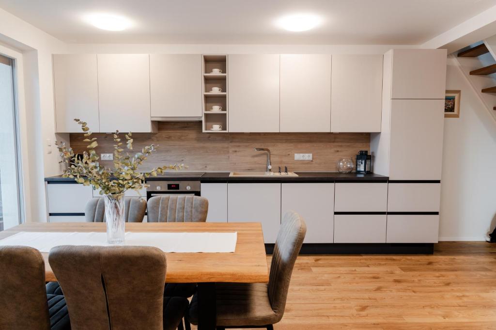 a kitchen with white cabinets and a wooden table with chairs at Apartments Naklo in Naklo