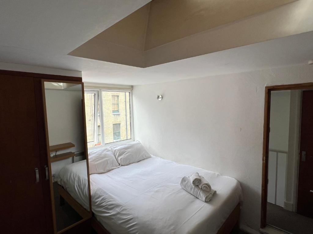 Schlafzimmer mit einem Bett mit weißer Bettwäsche und einem Fenster in der Unterkunft Stay in Bloomsbury2 in London
