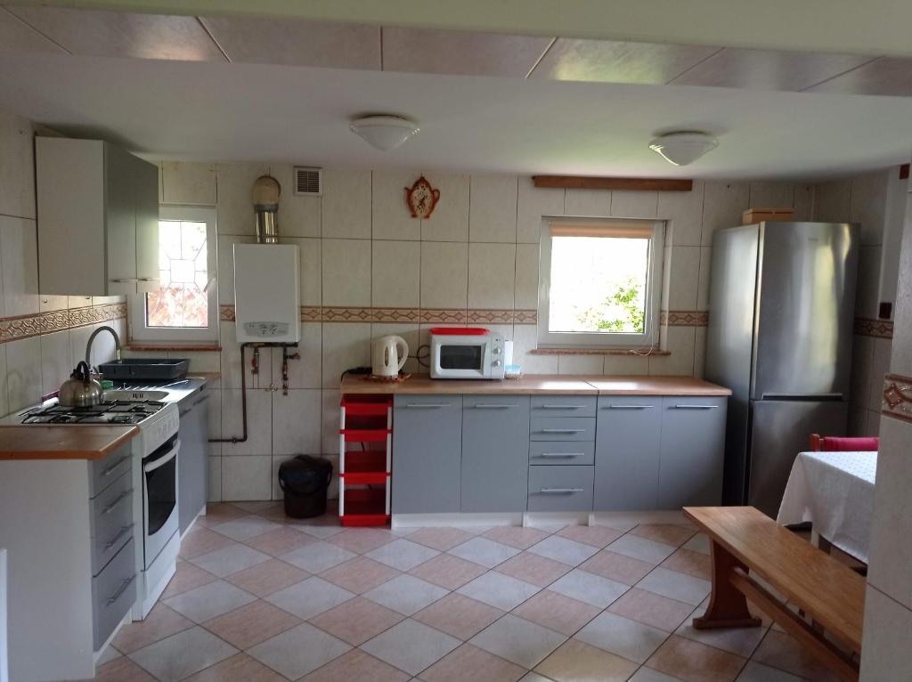 a kitchen with white cabinets and a stainless steel refrigerator at NIESULICE. DOMEK JEZIORO. NIESLYSZ in Niesulice
