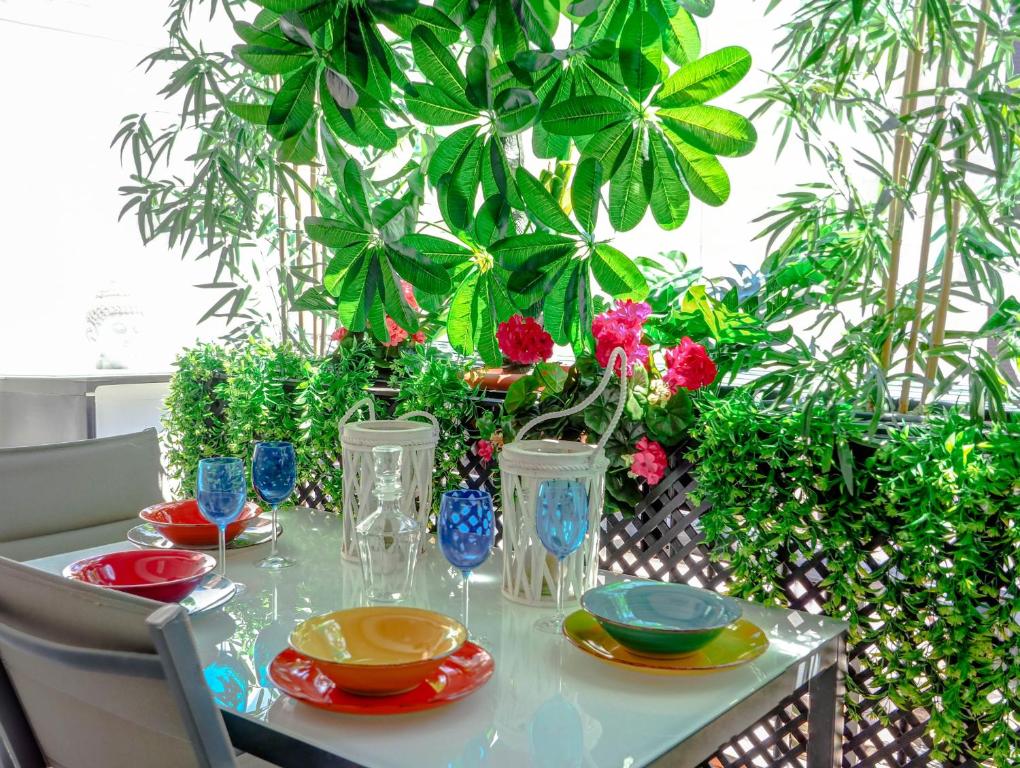 een tafel met platen en vazen erop met planten bij Flamingo Apartment by Hello Homes Sitges in Sitges