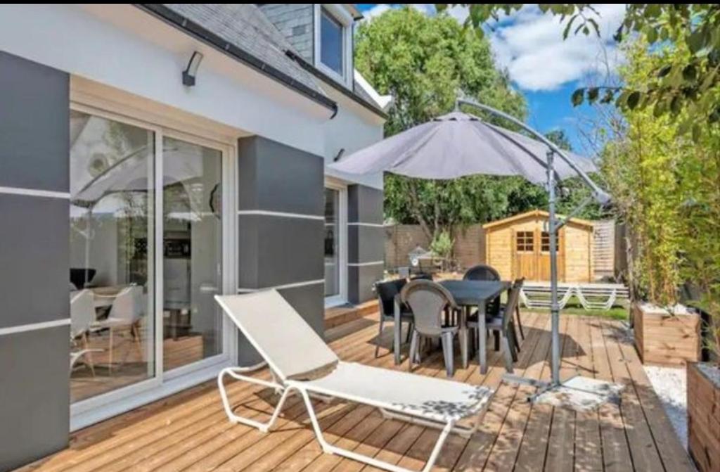 un patio avec une table, des chaises et un parasol dans l'établissement Les Cerisiers du Rouz, à Fouesnant