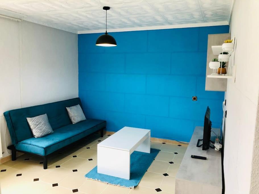 sala de estar con sofá y pared azul en Acogedor apartamento muy cerca del centro en Puertollano