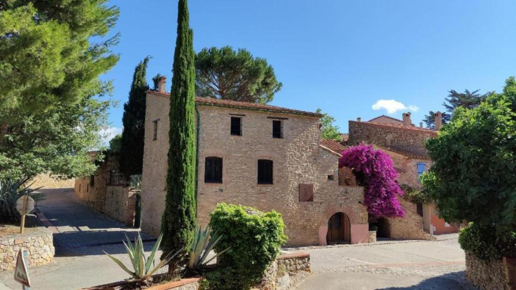 an old stone building with purple flowers on it at Les chambres du Mas Peu del Causse 