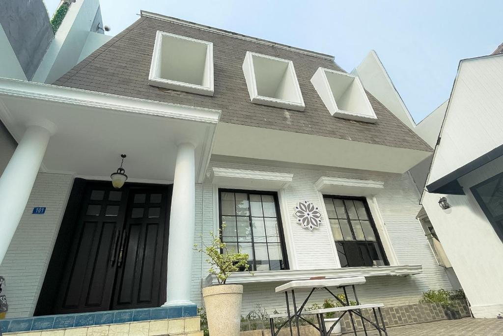 Mooi Inn City Center Surabaya في سورابايا: منزل أبيض مع باب ونوافذ سوداء