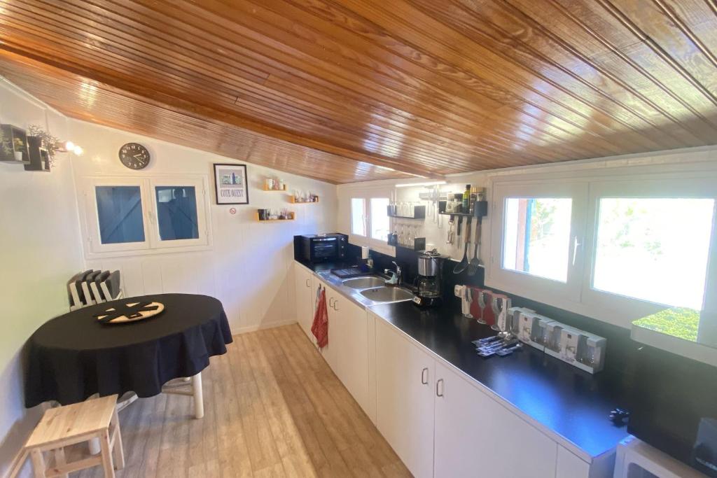 cocina con encimera negra y mesa en Chalet Rive Bellacha near Ouistreham beach, en Ouistreham