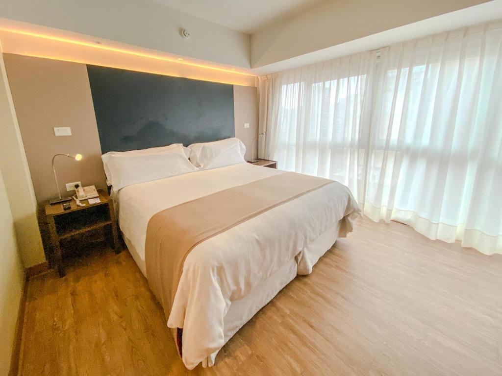 a bedroom with a large white bed and a window at Regente Palace Hotel in Buenos Aires