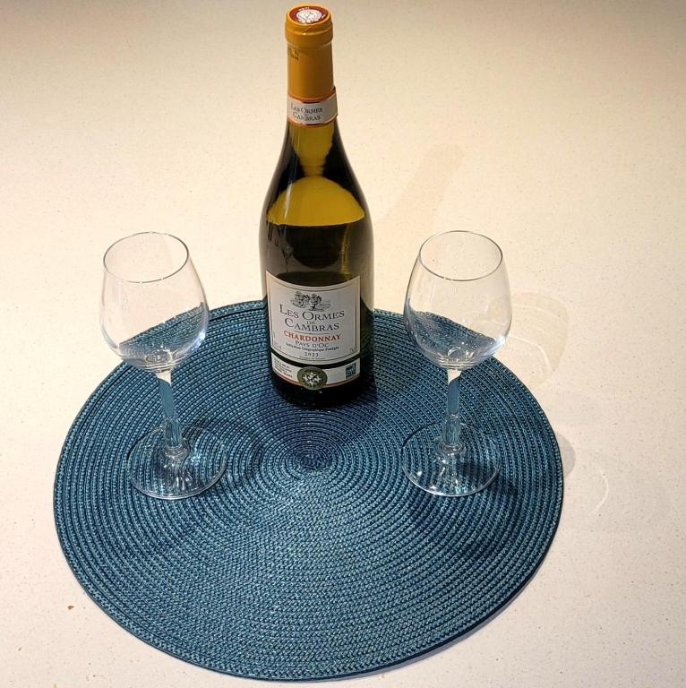 a bottle of wine and two wine glasses on a blue plate at L&#39;Harmonie de Naya, confort , parking privé in Bourges