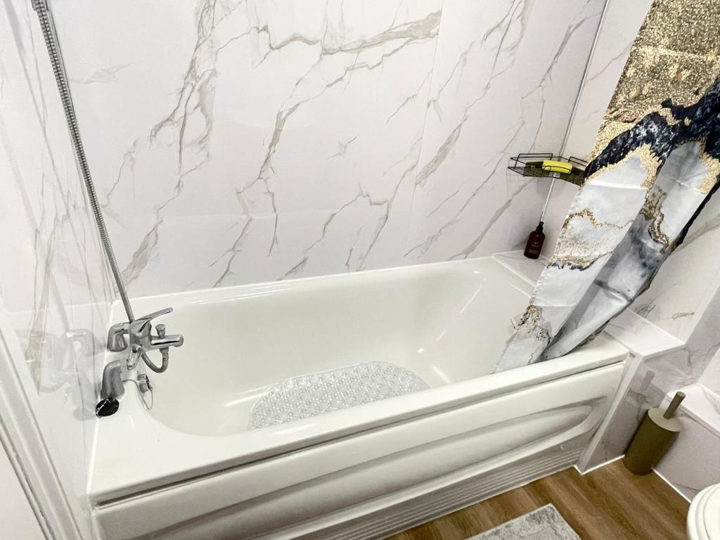 Westfield Grove 3 Bedroom Apartment في Goodmayes: حوض استحمام أبيض في حمام بجدران من الرخام