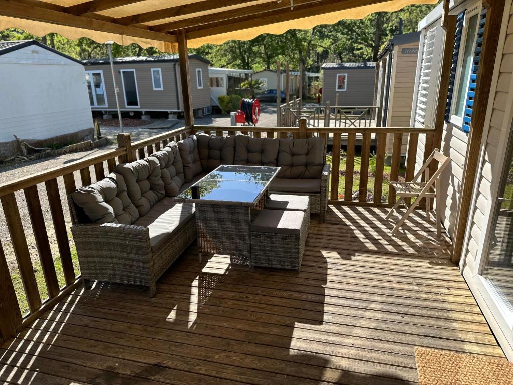 a patio with a couch and a table on a deck at Large Mobile Home on 4star Camping in Capbreton