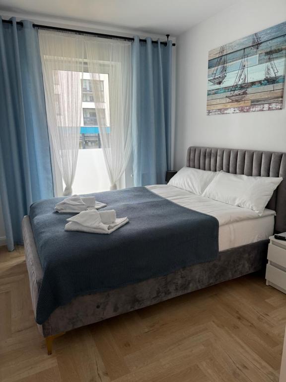 Schlafzimmer mit einem großen Bett und blauen Vorhängen in der Unterkunft Apartamenty Baltic Sea Navigator C1 in Kołobrzeg