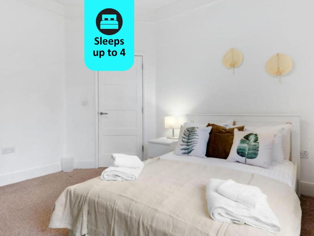 ein Schlafzimmer mit einem weißen Bett mit zwei Kissen in der Unterkunft Chic 1BR House in Hounslow - 12 mins From HEATHROW AIRPORT in Feltham
