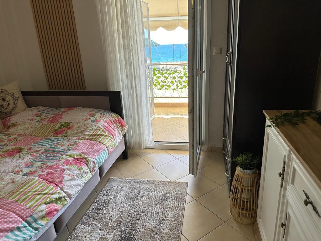 a bedroom with a bed and a door to a balcony at Изглед море студио Алекс Неа ПЕРАМОС in Néa Péramos