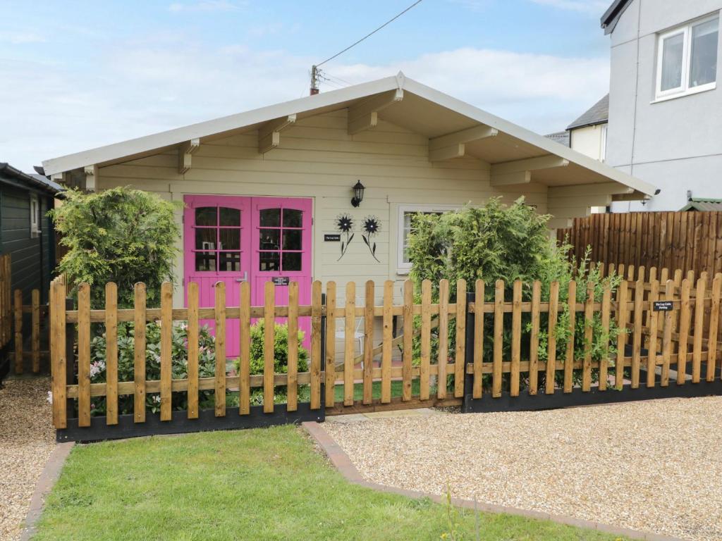 uma casa com uma porta rosa atrás de uma cerca em The Log Cabin em Swindon