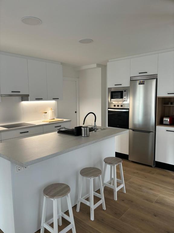 a kitchen with a counter and two stools in it at Apartamento Elkano 1 in Hernani