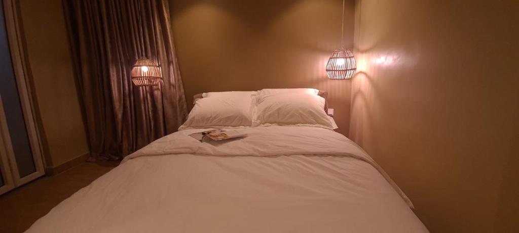 um quarto com uma cama com lençóis brancos e almofadas em Mindyourbusiness villa em Abuja