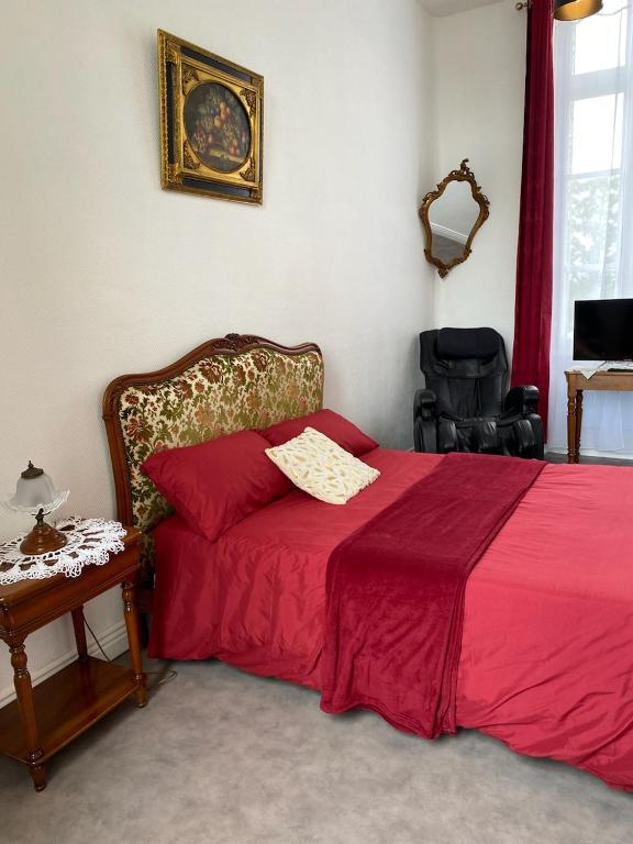 - une chambre avec un lit doté d'une couverture rouge et d'une table dans l'établissement Suite Bien être du Château de la Bouchatte, à Chazemais
