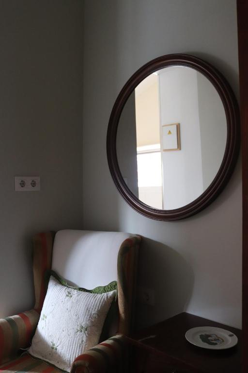 a mirror on a wall with a couch and a chair at Pension La Corredera in Tui