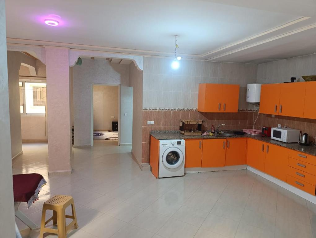 貝爾坎的住宿－appartement berkane，厨房配有橙色橱柜和洗衣机。